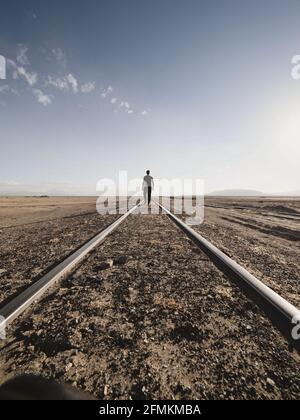 Männlicher Tourist, der auf verlassenen geraden Bahngleisen entlang läuft Trockene Anden Altiplano verlassene Landschaft in Julaca Uyuni Sur Lipez Potosi Bolivien Stockfoto