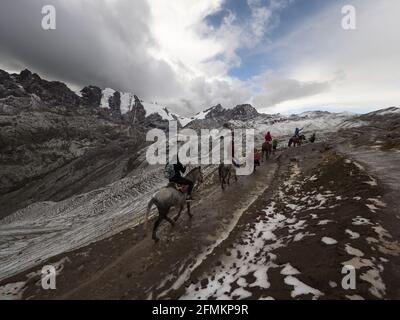 Gruppe von Touristen reiten durch verschneite Winterwunderland Landschaft Auf dem Pfad zum Rainbow Mountain Vinicunca in der Nähe von Cusco Pitumarca Peru Und Stockfoto