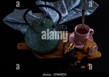 Am Valentinstag erfrischendes, hausgemachtes Frühstück für Paare mit grüner Teekannen aus Keramik, Schokoladenkeksen und herzförmigen Keks im Vintage-Look Stockfoto