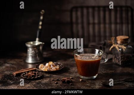 Kaffee in einem Glas mit Zucker und Kaffeebohnen auf Dunkler Hintergrund Stockfoto