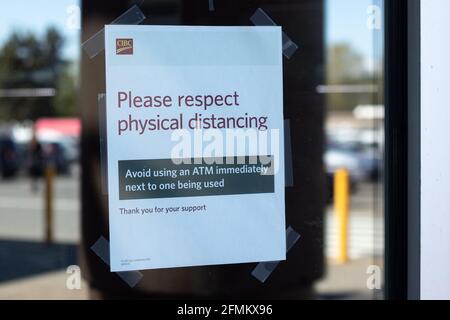 Courtenay, Kanada - April 22,2021: Ansicht des Schildes auf dem Fenster Bitte beachten Sie die physische Entfernung mit einem Geldautomaten Stockfoto