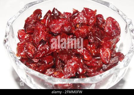 Getrocknete rote Preiselbeere in einer runden dicken Glasschale mit weißem Hintergrund gehäuft. Stockfoto