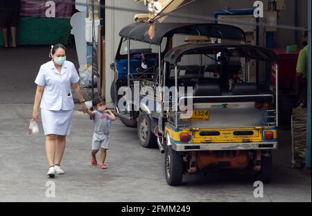 SAMUT PRAKAN, THAILAND, JULI 20 2020, EINE Frau mit einem kleinen Kind geht um die Station eines Motordreirads - Tuk Tuk Stockfoto