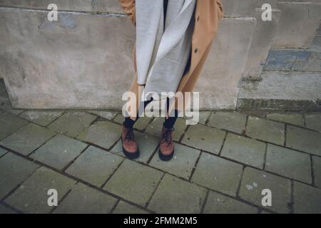 Beine einer Frau, beiger Kaschmirmantel, weißer warmer Schal, braune Stiefel für den Herbst, Street Fashion Stockfoto
