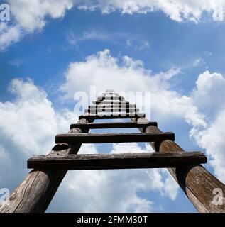 Holzleiter, die hoch oben in den himmlisch aussehenden blauen Himmel und weiße Wolken führt, Erfolgskonzept Stockfoto