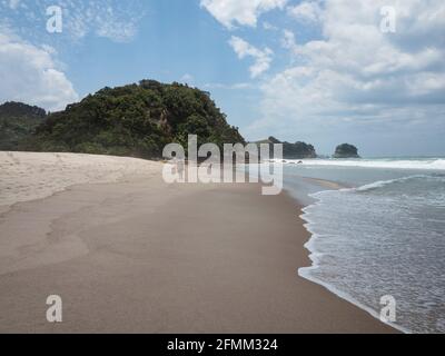 Weibliche Touristen, die am weißen Sandstrand des pazifischen Ozeans in Whiritoa spazieren In Hauraki Coromandel Peninsula Waikato Nordinsel Neuseeland Stockfoto