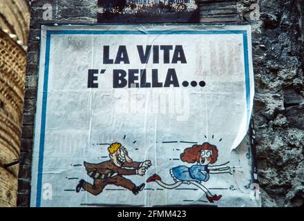 Poster an einer Wand in Perugia: La Vita E' Bella - das Leben ist schön. Ein Mann läuft einer Frau hinterher. 1984 - Christoph Keller Stockfoto