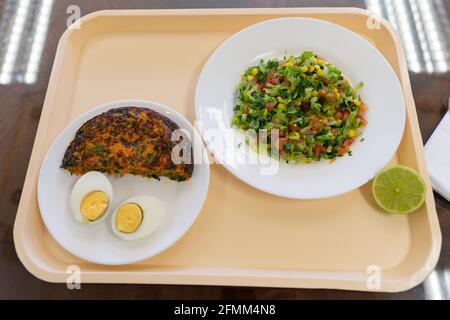 Tablettenmenü mit Karotten-Omelett, gekochtem Ei und Salattellern. Mittagspause im Werkskonzept Stockfoto