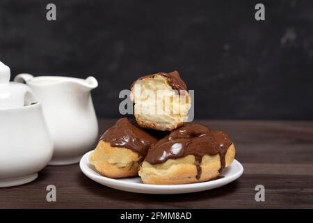 Eclairs mit Schokoladenüberzug und Buttercreme auf dem Servierteller Stockfoto