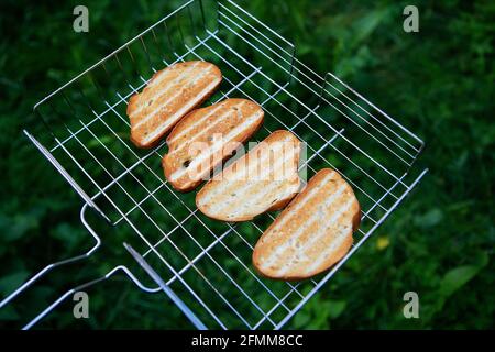 Gegrillter Toast auf dem Drahtgitter. Erholung im Freien. Lagerfeuer, Grill, lecker Stockfoto