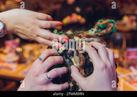 Rückansicht eines Teenagers mit dunklen langen Haaren Und eine Frisur aus farbigen Zöpfen drinnen Stockfoto