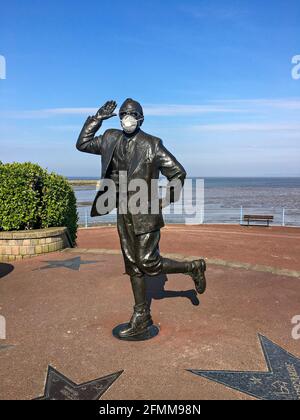 Statue am Meer in Morecambe des Komikers Eric Morecambe trägt eine schützende Gesichtsmaske Stockfoto