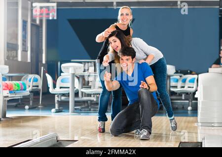 Gruppe von Freunden in einer Bowlingbahn, Spaß haben, die Mädchen jubeln dann er bekommen einen Streik Stockfoto