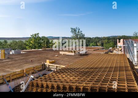 Verstärkendes Stahlgeflecht auf der Baustelle in grüner Landschaft auf blauem Himmel Hintergrund. Rostbraunes Gitter für Stahlbeton auf dem im Bau befindlichen Haus. Stockfoto