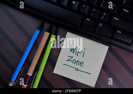 WiFi-Zone auf Haftnotizen auf Holztisch isoliert schreiben. Stockfoto