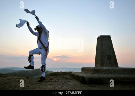 Mit der Regel von sechs in Betrieb und covid Einschränkungen noch an Ort und Stelle Mitglieder von Gloucestershire Morris Männer trafen sich auf Painswick Beacon vor da Stockfoto