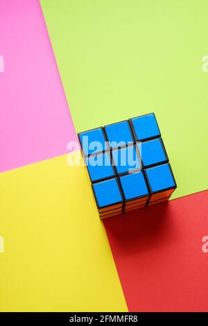 Rubik's würfelblaue Seite auf einem rosafarbenen, rot-gelben Tisch. Stockfoto