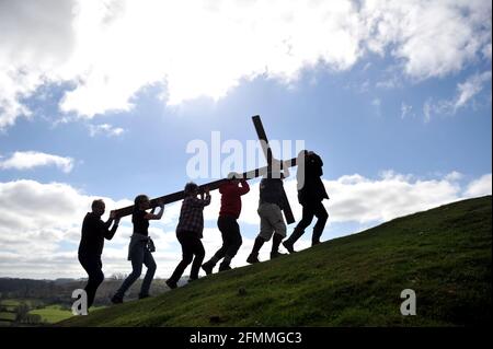 Am Karfreitag vor dem Ostersonntag ein Holzkreuz auf den Cam Peak tragen, bei einem Spaziergang von Witness, Gloucestershire Stockfoto