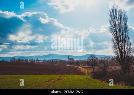 Blick auf Felder und Hügel mit dem Dorf und die Berge Im Hintergrund Stockfoto