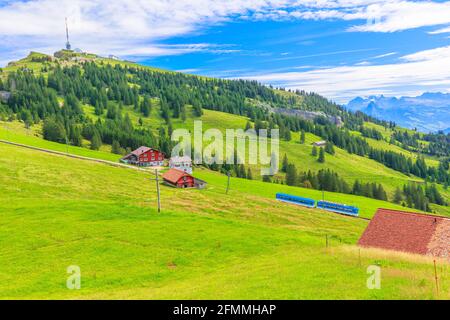 Malerische Landschaft zwischen Alpen, Täler der Rigi Bergbahnen und blauen Zahnradbahn. Rigi Kulm Gipfel und Telekommunikationsturm im Hintergrund Stockfoto