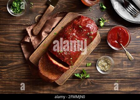 Hackbraten mit Glasur auf Schneidebrett auf Holzhintergrund. Draufsicht, flach liegend, Nahaufnahme Stockfoto