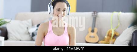 Frau in Kopfhörer und Tracksuit Notizen auf Notebook auf Online Gewichtsverlust Trainingskonzept Stockfoto