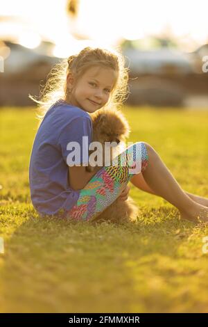 Kleines Mädchen hält Welpen. Kind mit Hund. Familie und Haustiere auf Parkrasen. Kinder- und Tierfreundschaften Stockfoto