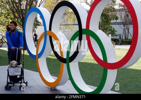 Tokio, Japan. Mai 2021. Ein Mann, der mit einer Gesichtsmaske einen Hundewagen schiebt, geht an den Olympischen Ringen in der Nähe des Nationalstadions in Tokio vorbei. Kredit: SOPA Images Limited/Alamy Live Nachrichten Stockfoto