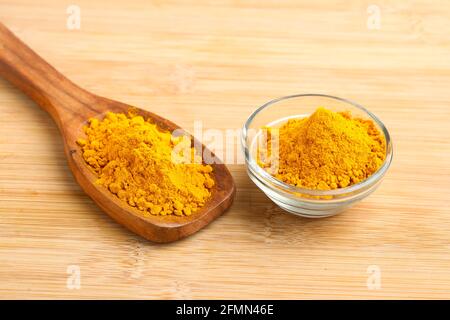 Kurkuma-Pulver in Holzlöffel und Glasschale auf weißem Hintergrund. Stockfoto