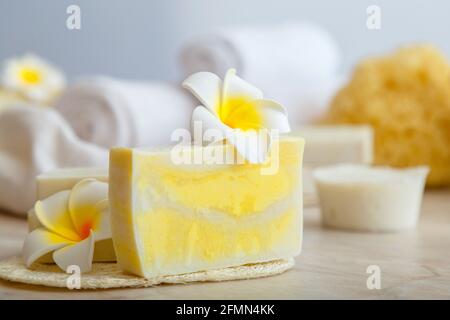 Handgemachte Seife, Spa-Badeprodukte weiße Handtücher tropische Plumeria Blumen auf Marmortisch im Badezimmer. Eco Beauty Kosmetik für Wellness Gesundheit Hautpflege. Stockfoto