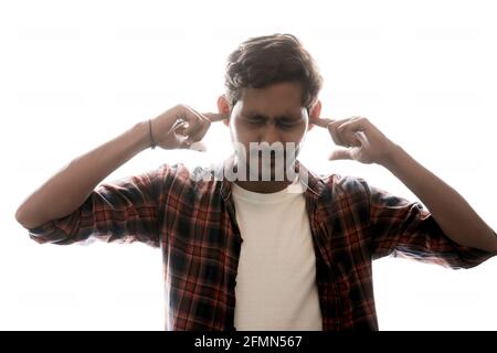 Junger inder, der Finger in die Ohren drückt und nicht will Um noch mehr zu hören Stockfoto