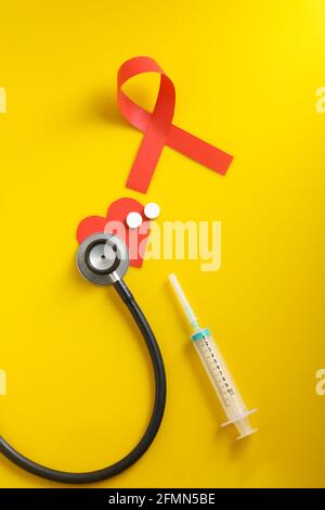 Arbeitsplatz des Arztes mit Stethoskop, Blistertabletten, Spritze auf gelbem Hintergrund. Stockfoto