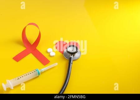 Arbeitsplatz des Arztes mit Stethoskop, Blistertabletten, Spritze auf gelbem Hintergrund. Stockfoto