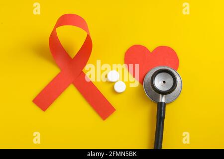 Arbeitsplatz des Arztes mit Stethoskop, Blistertabletten, Spritze auf gelbem Hintergrund. Stockfoto