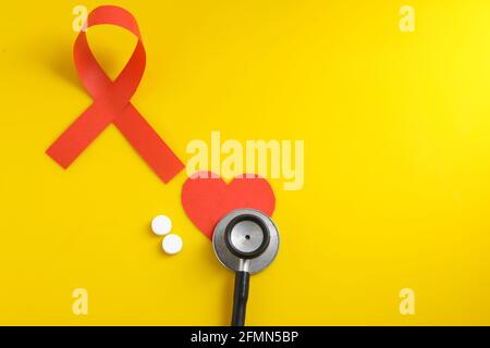 Arbeitsplatz des Arztes mit Stethoskop, Blistertabletten, Spritze auf gelbem Hintergrund. Stockfoto