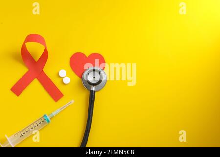 Arbeitsplatz des Arztes mit Stethoskop, Blistertabletten, Spritze auf gelbem Hintergrund. Stockfoto