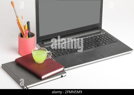 Laptop und Tagebuch mit einer Tasse grünem Tee. Work from Home Konzept Stockfoto