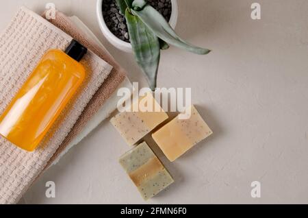 Orange Shampoo, Gel, flüssige Seife aus natürlichen Zutaten in einer transparenten Flasche liegt auf einem Stapel von beigen Handtücher, gibt es Stücke von natürlichen so Stockfoto