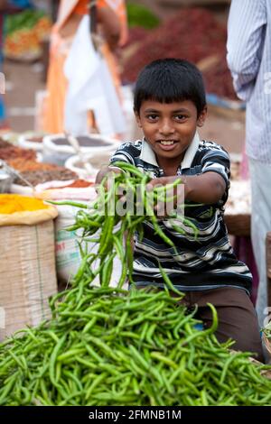 Porträt eines Jungen, der frische Chilis verkauft, Mapusa Friday Market, North Goa, Indien. Stockfoto