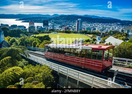 Die Wellington Cable Car-Standseilbahn direkt vor der Kelburn Station mit dem Cricket Ground des Kelburn Park und der Stadt Wellington im Hintergrund. Nein Stockfoto