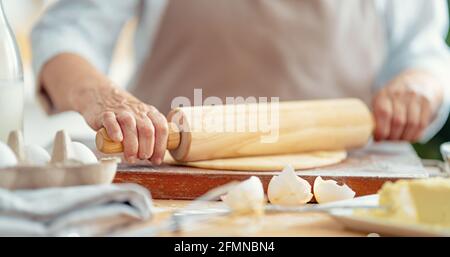 Nahaufnahme des Bäckers funktioniert. Hausgemachtes Brot. Hände, die Teig auf Holztisch vorbereiten. Stockfoto