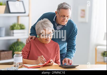 Ältere Ehepaare sitzen am Schreibtisch mit einem Papierbeleg in den Händen berechnen Kosten, Verwaltung der Familie Budget. Stockfoto