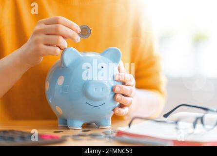 Frau sitzt am Schreibtisch mit Sparschwein. Konzept der Verwaltung des Familienbudgets. Stockfoto