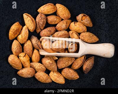 Draufsicht auf Holzlöffel in rissigen Mandelbrocken Schwarze Platte Stockfoto