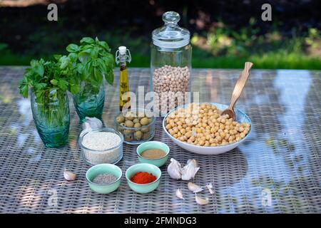 Eine Reihe von Zutaten für die Zubereitung von Hummus-Snacks: Kichererbsen, Tahini, Gewürze, Knoblauch, Petersilie, Olivenöl . Rezept für eine vegetarische Mediterrane Stockfoto