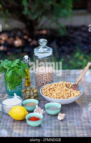 Eine Reihe von Zutaten für die Zubereitung von Hummus-Snacks: Kichererbsen, Tahini, Gewürze, Knoblauch, Petersilie, Olivenöl . Rezept für eine vegetarische Mediterrane Stockfoto