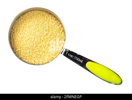 Draufsicht auf rohe nordafrikanische Couscous-Körner in der Messung cup-Ausschnitt auf weißem Hintergrund Stockfoto