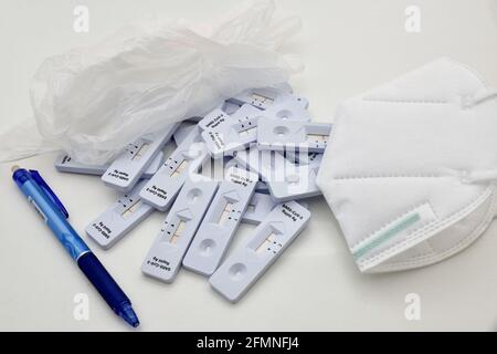 Haufen von Corony Virus Rapid Antigen Testkits, die auf der Laboroberfläche liegen. Mit Handschuhen, blauem Stift und weißer Schutzmaske als Arzt Nee Stockfoto