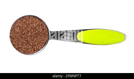 Draufsicht auf Vollkorn-Teff-Samen bei der Messung des Esslöffelausschnitts Auf weißem Hintergrund Stockfoto