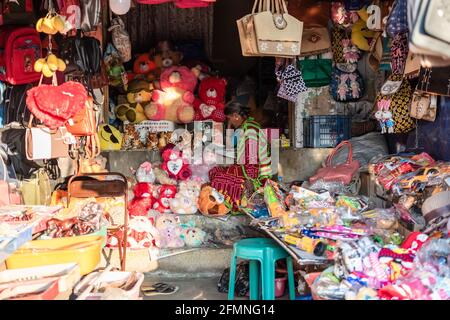 Mysore, Karnataka, Indien - Januar 2019: Eine indische Kauffrau in einem Geschäft, das billige Ledertaschen, Stofftiere und verschiedene bunte Waren verkauft. Stockfoto